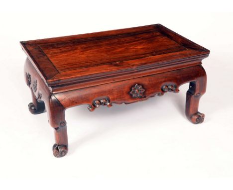 A Chinese padouk wood rectangular low tea table, panel top with shallow gallery, shaped frieze carved with flowerheads and sc