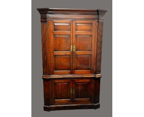 A George III oak splay fronted floor standing corner cupboard, moulded cornice above two pairs of raised and fielded panel do