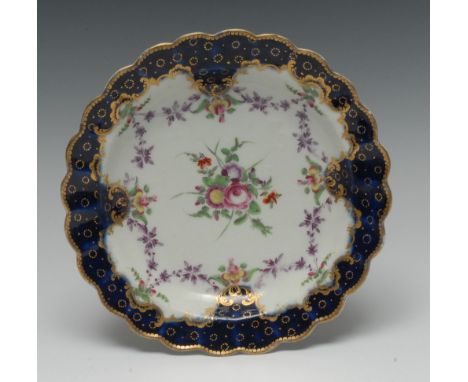 A Worcester shaped circular plate, painted with central flowers surrounded by puce floral festoons, blue border with Peacock 