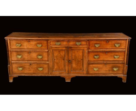 A George III mahogany crossbanded oak dresser, moulded rectangular top above an arrangement of drawers and cupboards, brass b