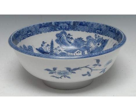 A Chinese circular bowl or basin, painted in underglaze blue with pagodas, figures and sampans in a monumental landscape, the