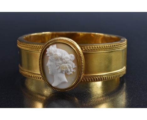 A carved shell cameo topped hinge bangle, central oval portrait of Flora within beaded frame, above a cast hollow hinge body,