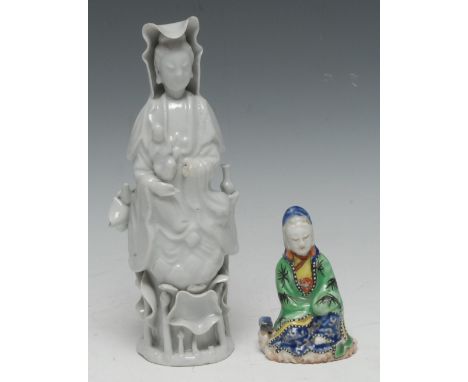 An early 18th century Chinese Blanc de Chine porcelain figure, of Guanyin, modelled holding the infant allegorical of Bodhisa