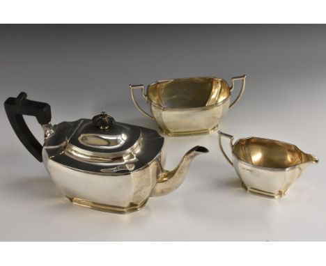 A George V silver three piece tea service, comprising teapot, milk jug and sugar basin, incurved angles, angular scroll handl