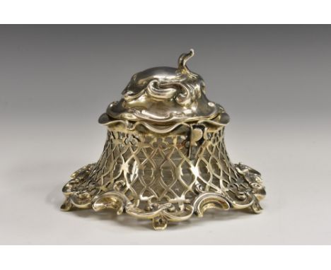 An early Victorian Rococo Revival silver inkwell, hinged cover flanked by pen stands, pierced side, leafy scroll border, glas