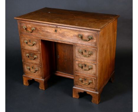 A George III mahogany kneehole desk, crossbanded moulded top above a frieze drawer, cupboard to niche, flanked by two rows of