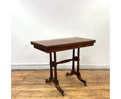 A George IV rosewood card table in the manner of George Bullock, the hinged rectangular top with an inlaid border of entwined