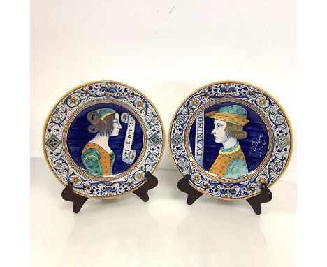 A pair of Deruta maiolica portrait plates, 20th century, the wells painted with a lady and gentleman with a Latin motto, pain