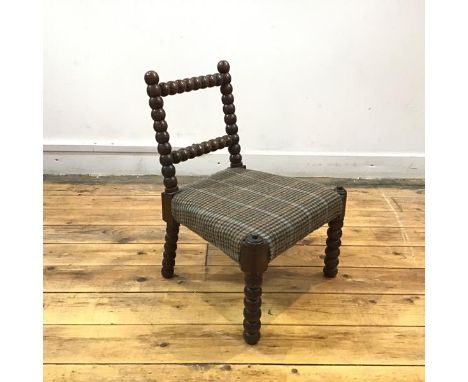 A 19th century child's bobbin chair, the rectangular back above a woven tweed seat. 48cm by 38cm by 34cm