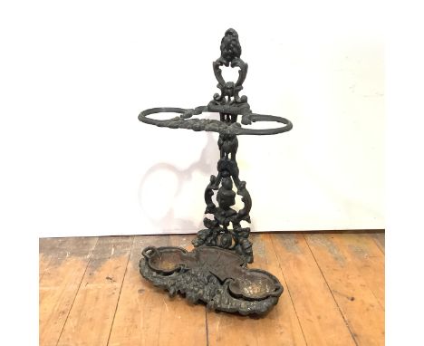 A Victorian cast-iron stick stand, with twin hoops, cast with mask, floral and foliate decoration and with original drip tray