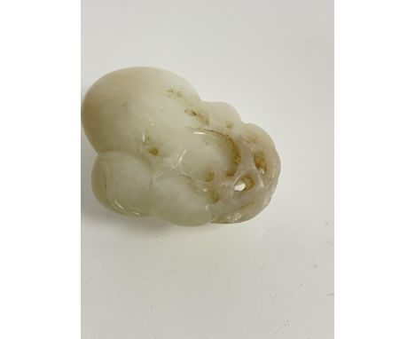 A Chinese pale celadon jade carving of a peach, the plump fruit with pierced trailing foliage. Length 4.5cm