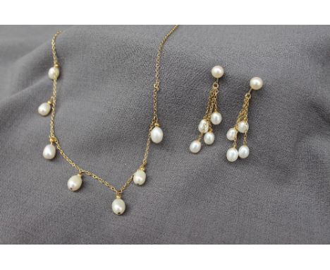 A pearl and yellow metal necklace set with seven oval pearls on a yellow metal chain with matching earrings 