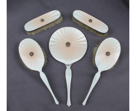 A George V silver and cream enamel part dressing table set, comprising a hand mirror, a pair of hair brushes and a pair of cl