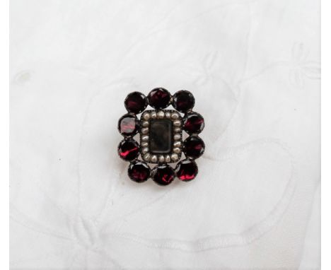 A Garnet and seed pearl set mourning brooch, with a central lock of hair 