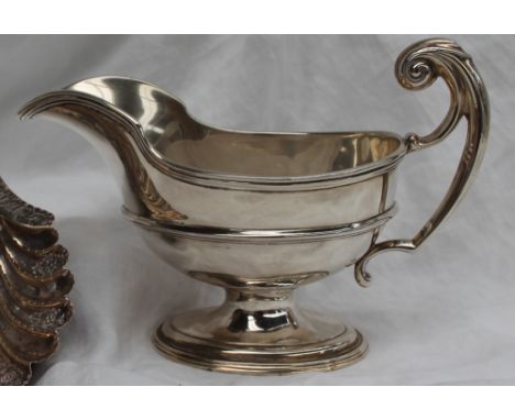 A silver sauce boat, with a line decorated rim and ring body with a leaf capped scrolling handle on a spreading foot, marks r