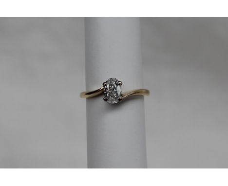 A solitaire diamond ring, the oval faceted diamond approximately 0.75 of a carat to a white metal four claw setting and 18ct 