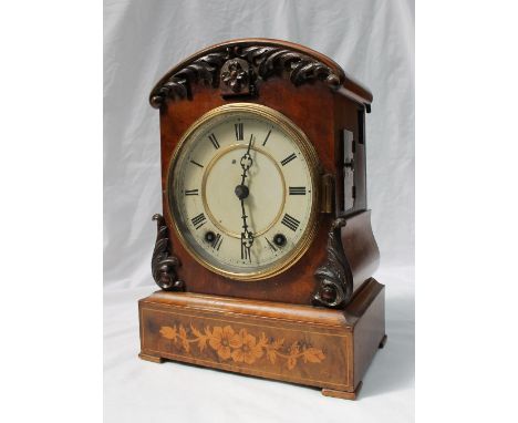 A Victorian walnut cuckoo clock, with an arched top, with leaf carving, the plinth with floral marquetry decoration, the circ