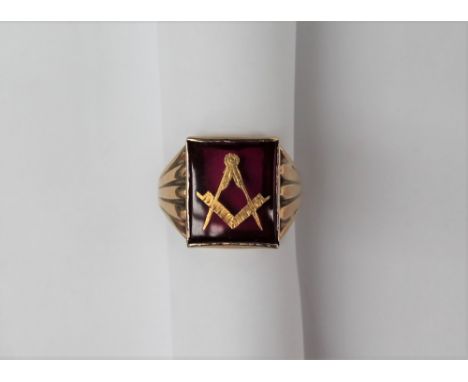 A 9ct yellow gold Masonic ring, the central red panel with gilt square and compass to a 9ct yellow gold setting and shank