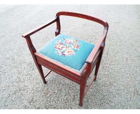 An Edwardian commode with upholstered seat decorated in a floral design (the commode lacking its internal fittings)