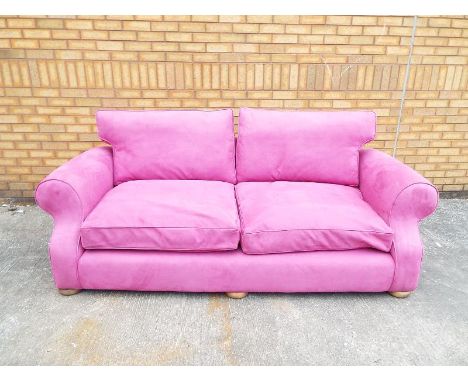 A Manuel Canovas pink faux suede three seater sofa, two loose back cushions, beech frame sitting on flat bun feet approx size