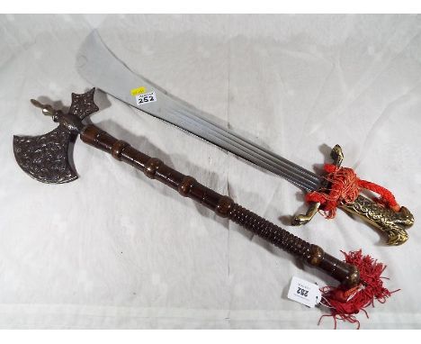 An ornamental axe with wooden turned handle and brass relief head and an ornamental scimitar (2)
