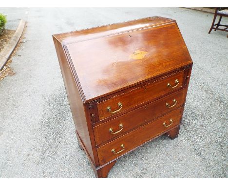 An Edwardian mahogany bureau with inlaid marquetry, the slope front on manual lopers opening to reveal a pigeon hole fitted i