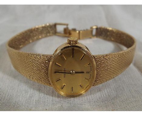 A lady's wristwatch, 9 carat gold case mounted on a 9 carat band, champagne oval dial with applied baton markers signed Tisso