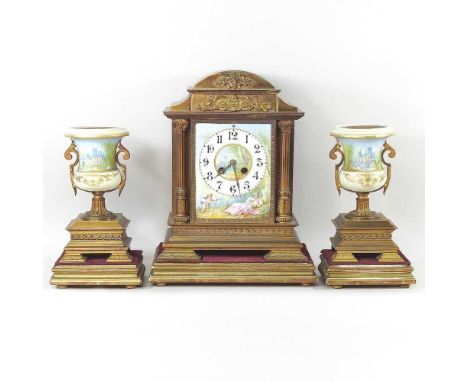 An early 20th century continental gilt three piece clock garniture, inset with painted porcelain panels, flanked by a pair of