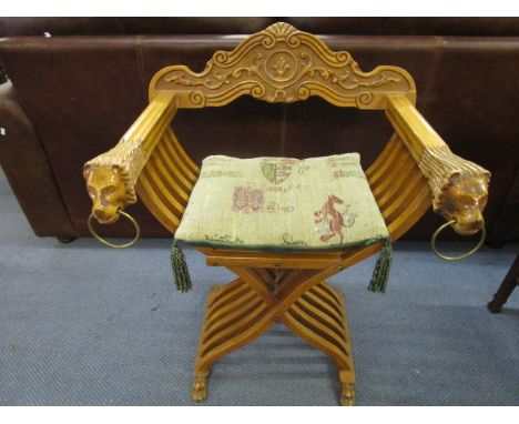 A light wood x framed folding campaign chair with lion head and ring arm terminal, lion paw feet and loose tapestry style cus