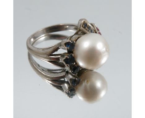 A cultured pearl ring, unmarked white mount, the 11mm diameter pearl with ruby and sapphire set cross over shoulders, finger 