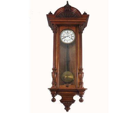 A mahogany cased Vienna style wall clock, the case having carved decoration, with white enamel dial, height 50ins
