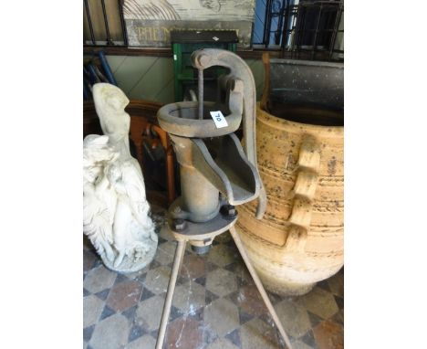 A small vintage cast iron hand operated water pump raised on tripod supports