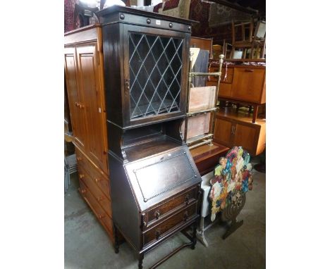 A small Edwardian/1920s oak bureau bookcase, the upper section enclosed by a leaded light diamond pattern door revealing two 
