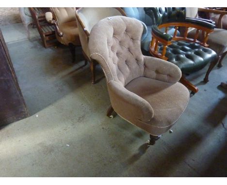 A Victorian button back drawing room chair with waisted arched back, upholstered finish and turned forelegs with white cerami