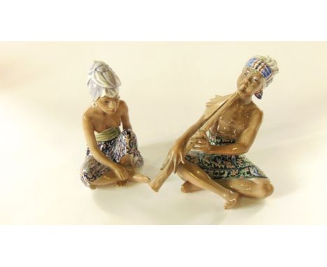 Two Copenhagen models of seated male and female eastern style characters, both wearing floral sarongs and turbans, he playing