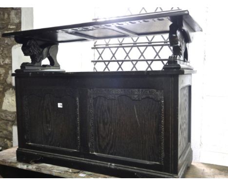 A reproduction dark stained oak monks bench with hinged panelled lid over lion supports and box seat