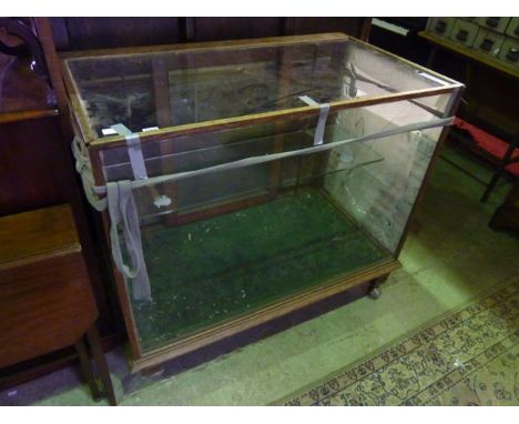 A vintage freestanding shop display cabinet/counter of rectangular form, oak framed with glazed panels and two sliding doors,