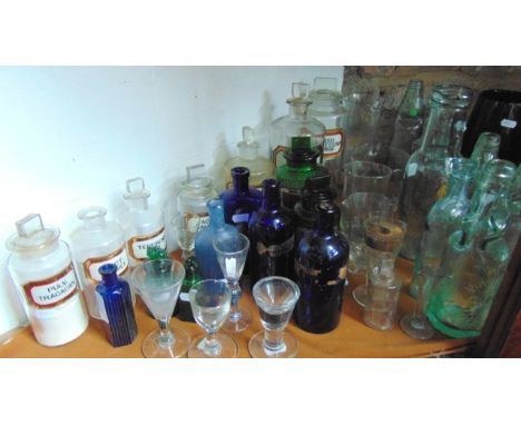 An interesting selection of glassware to include several antique clear glass chemist bottles with tablet shaped stoppers, bea