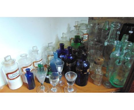 An interesting selection of glassware to include several antique clear glass chemist bottles with tablet shaped stoppers, bea