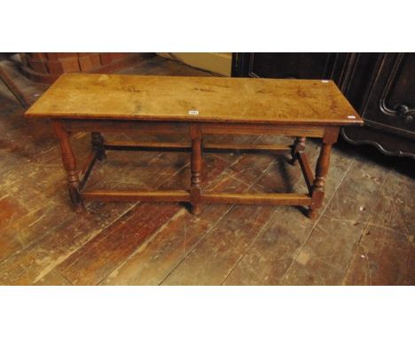 An old English oak bench/centre table of rectangular form raised on six turned vase shaped supports united by an outer rail, 