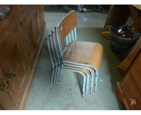 A set of four vintage child's stacking school chairs with steel frames and laminated plywood seats and back splats
