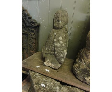 A weathered carved stone figure of a male character wearing a single buttoned cloak, 41 cm high approximately