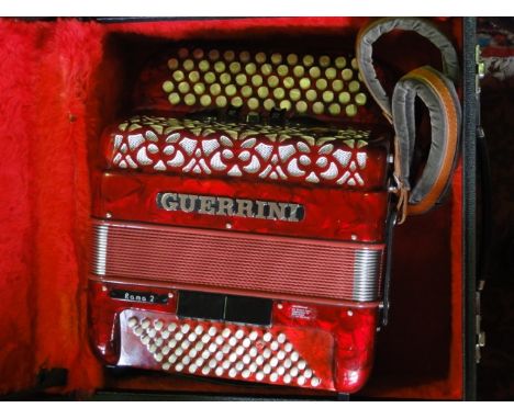 A vintage accordion in red shellac casing bearing lettering Guerrini, also marked Rama 2, set within a further felt lined cas