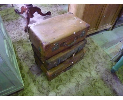Three vintage fibre and leather reinforced suitcases of varying size, one with brass fittings