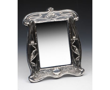 An Art Nouveau easel back mirror, William Neale, Birmingham, 1910, the shaped frame embossed with water lilies, birds, flower