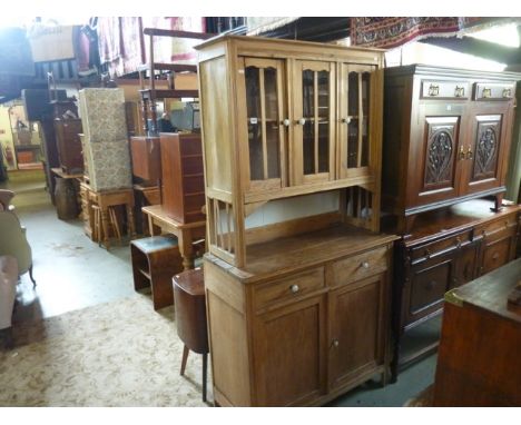 A continental stripped pine kitchen dresser, the upper section enclosed by three glazed and barred panelled doors revealing a