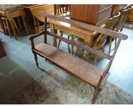 A hall bench with mahogany plank seat, raised on four turned tapered legs, later adapted with raised bar back, open arms oak 