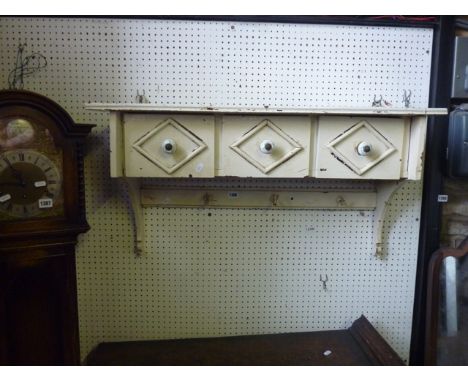 A vintage painted wall shelf fitted with three deep frieze drawers with lozenge mouldings and decorative hand painted ceramic