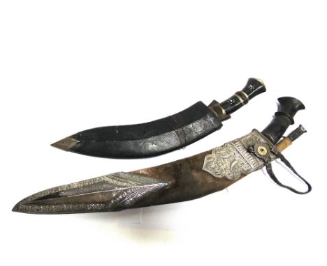 A NEPALESE KUKRI  the 42cm typically curved blade with a carved wood grip, in a leather scabbard with ornate silver coloured 