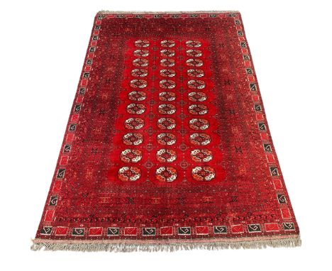 An Afghan carpet, circa 1930-1950, the madder field with eleven rows of three medallions, within multiple borders, 291 x 201c